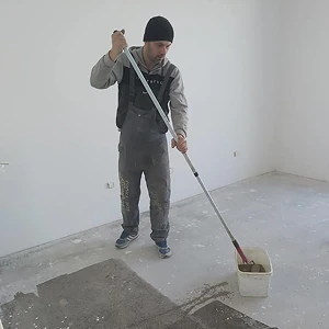 Radnik koristi alat za nivelisanje podloge - ujednačavanje površine poda