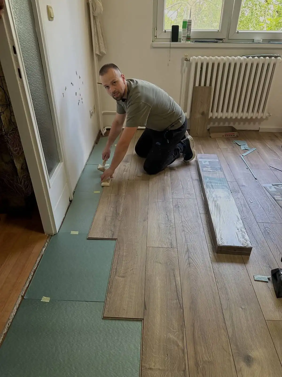 Radnik polaže laminat tamne nijanse - estetski sklad i kvalitetni materijali